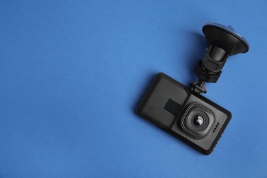 Modern car dashboard camera with suction mount on blue background, top view. Space for text