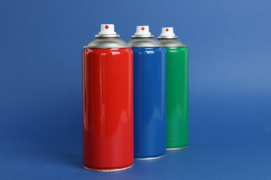 Colorful cans of spray paints on blue background