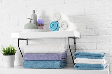 Shelves with clean towels and toiletries on brick wall