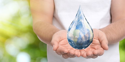 World Water Day. Man holding icon of drop with Earth image inside on blurred green background, closeup