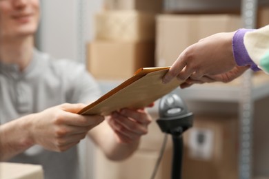 Worker giving parcel to woman at post office, closeup