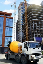 Photo of Concrete mixer truck and tower cranes near unfinished building at construction site