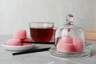 Glass cloche with delicious mochi on grey table, space for text. Traditional Japanese dessert
