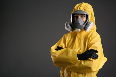 Woman wearing chemical protective suit on grey background, space for text. Virus research