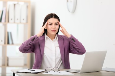 Woman suffering from migraine at workplace in office