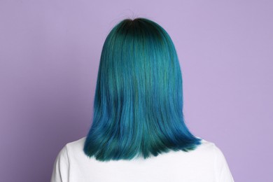 Photo of Woman with bright dyed hair on lilac background, back view