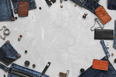 Frame made of garment accessories and cutting details for jeans on grey marble background, flat lay. Space for text