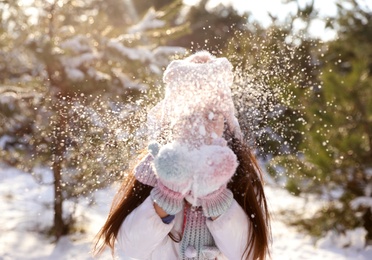 Cute little girl playing with snow in winter forest