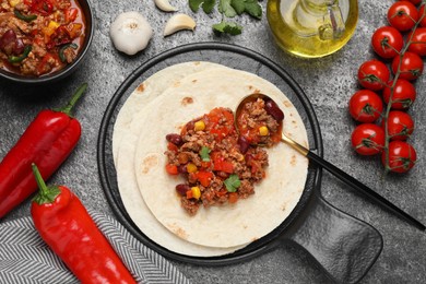 Tasty chili con carne with tortilla and ingredients on grey table, flat lay
