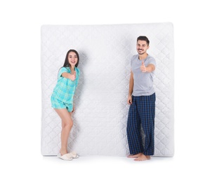 Young couple with comfortable mattress isolated on white