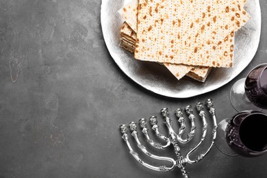 Matzos, red wine and menorah on grey table, flat lay. Space for text