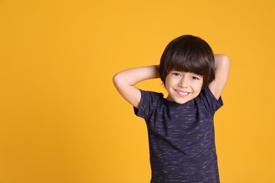 Portrait of cute little boy on yellow background, space for text