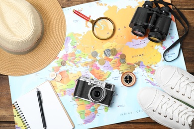 Flat lay composition with world map and different travel accessories on wooden table. Planning summer vacation trip