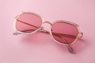 New stylish sunglasses on pink background, closeup. Fashionable accessory