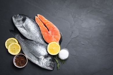 Fresh dorado fish, salmon and ingredients on black slate background, flat lay. Space for text