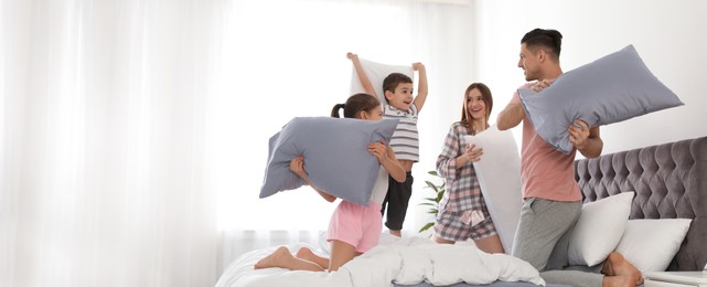 Happy family having pillow fight in bedroom, space for text. Banner design