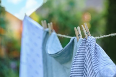 Washing line with drying shirts against blurred background, focus on clothespin