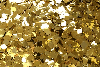 Bright golden confetti as background, top view