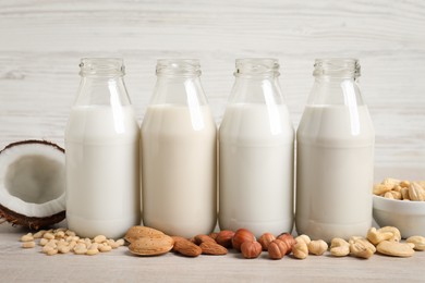 Photo of Different nut milks in glass bottles on white table