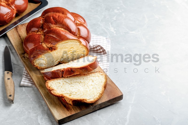 Photo of Cut homemade braided bread on grey table, space for text. Traditional Shabbat challah