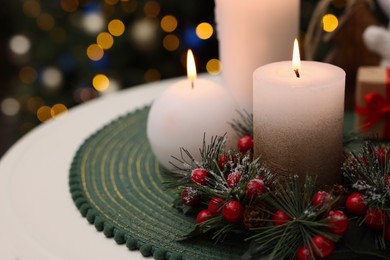 Beautiful burning candles and Christmas decor on white table against festive lights. Space for text