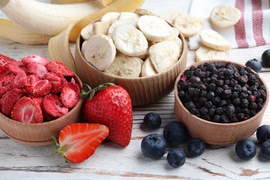 Different freeze dried and fresh fruits on white wooden table, closeup