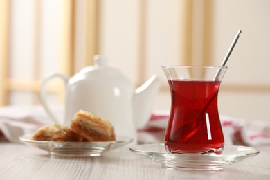 Photo of Glass of traditional Turkish tea and sweet baklava on white wooden table indoors. Space for text