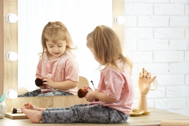 Cute little girl playing with cosmetics in dressing room