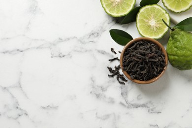 Dry bergamot tea leaves and fresh fruits on white marble table, flat lay. Space for text