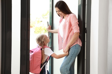 Happy mother and little child with school bag in doorway