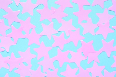 Pink star shaped confetti on light blue background, flat lay
