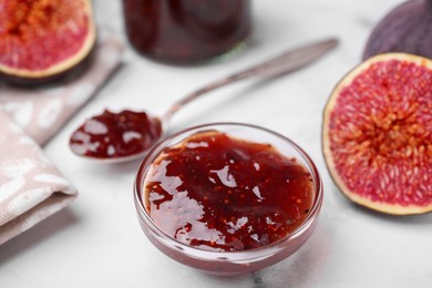 Photo of Tasty sweet fig jam and fruits on white marble table, closeup