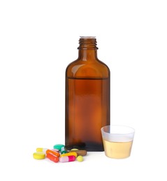 Photo of Pills, bottle with measuring cup of syrup on white background. Cough and cold medicine