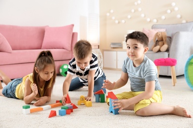 Cute little children playing with building blocks on floor, indoors