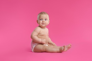 Cute baby in dry soft diaper sitting on pink background