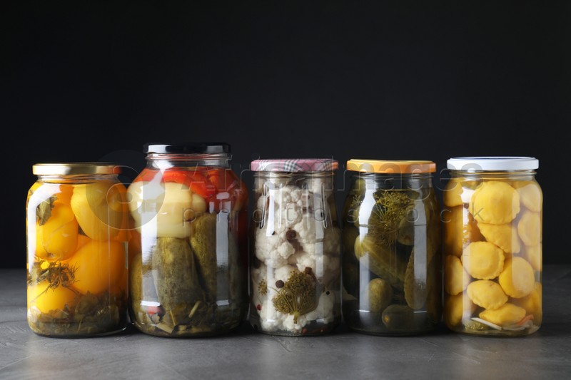 Jars of tasty pickled vegetables on grey table