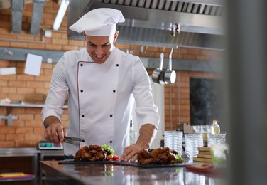 Photo of Professional chef with delicious fried chicken wings in restaurant kitchen