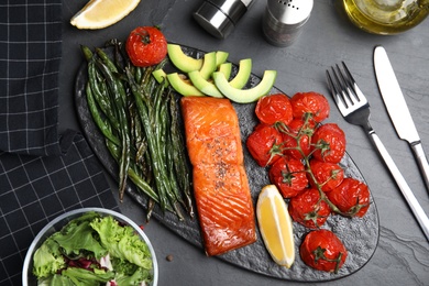 Photo of Tasty cooked salmon and vegetables served on black table, flat lay. Healthy meals from air fryer