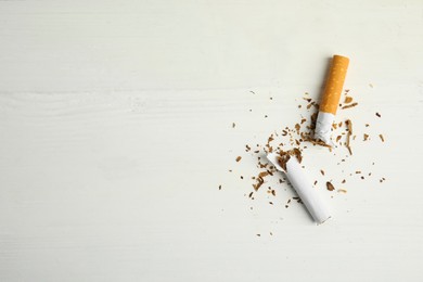Broken cigarette on white table, flat lay with space for text. Quitting smoking concept