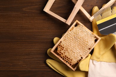 Honeycomb frames and beekeeping tools on wooden table, flat lay. Space for text