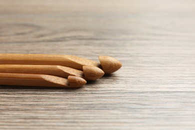 Three crochet hooks on wooden table, closeup. Space for text