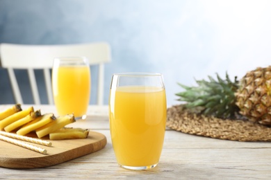 Delicious pineapple juice in glass on white wooden table