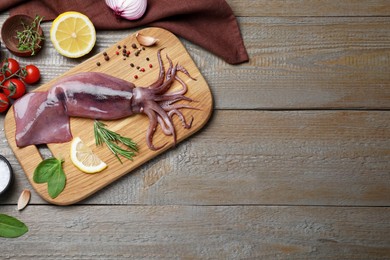 Photo of Flat lay composition with fresh raw squid and garnish ingredients on wooden table. Space for text