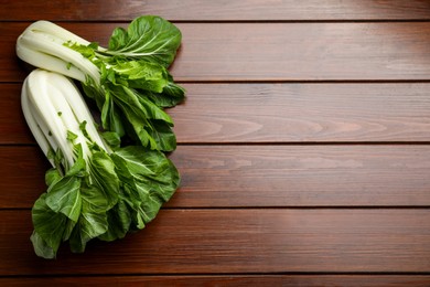 Fresh green pak choy cabbages on wooden table, flat lay. Space for text