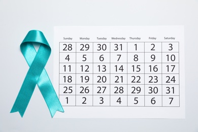 Teal awareness ribbon and calendar on white background, top view. Symbol of social and medical issues