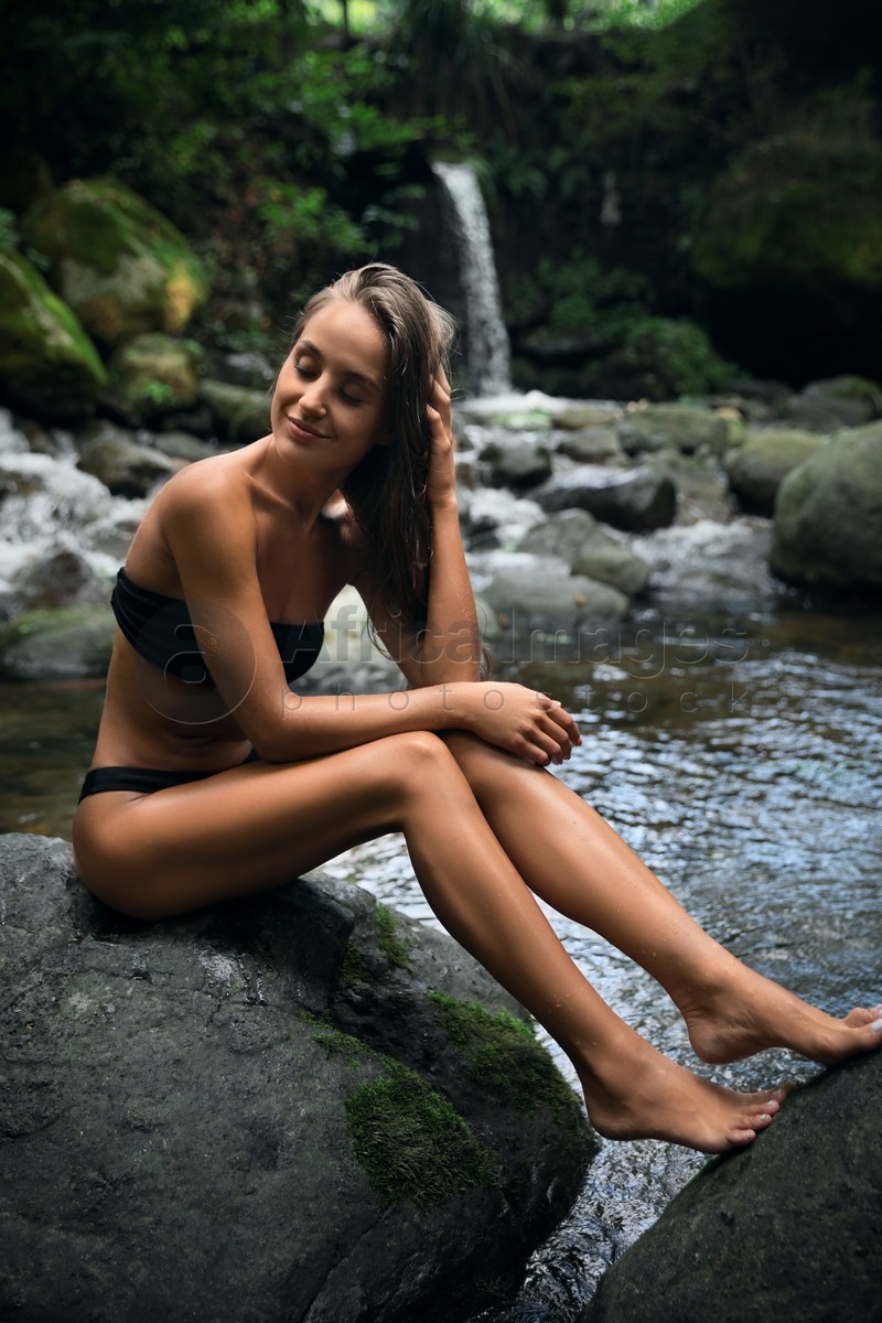 Photo of Beautiful young woman relaxing near mountain waterfall outdoors