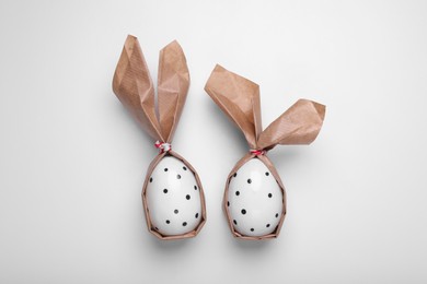 Photo of Easter bunnies made of craft paper and eggs on white background, flat lay