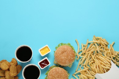 Flat lay composition with delicious fast food menu on light blue background. Space for text