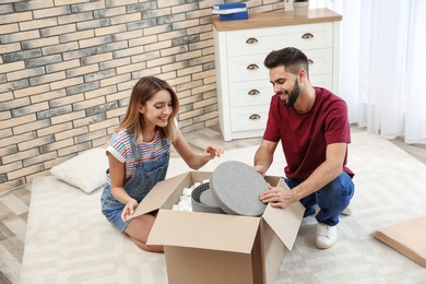 Young couple opening parcel on floor at home