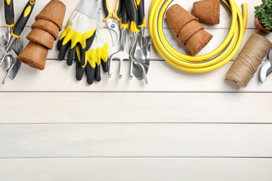 Flat lay composition with gardening tools on white wooden background, space for text